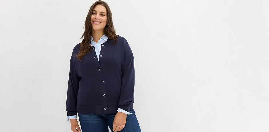 Dunkelblaue Strickjacke über weißer Bluse, kombiniert mit klassischer Jeans.
