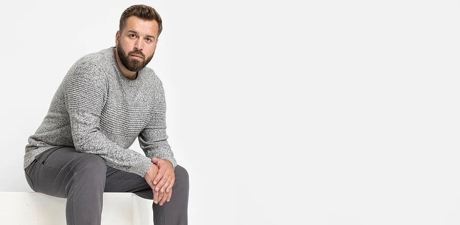 Grauer Strickpullover und graue Hose bilden ein lässiges Outfit.