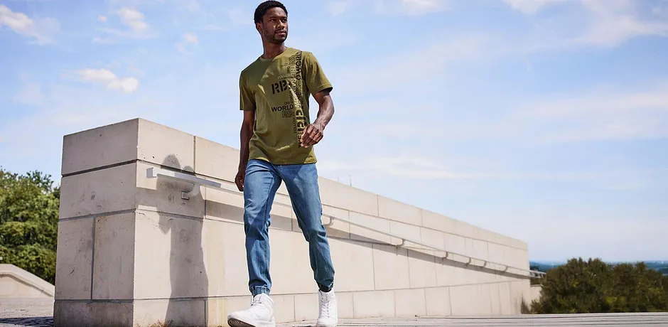 Lässiger Look mit olivgrünem T-Shirt und hellblauen Jeans. 