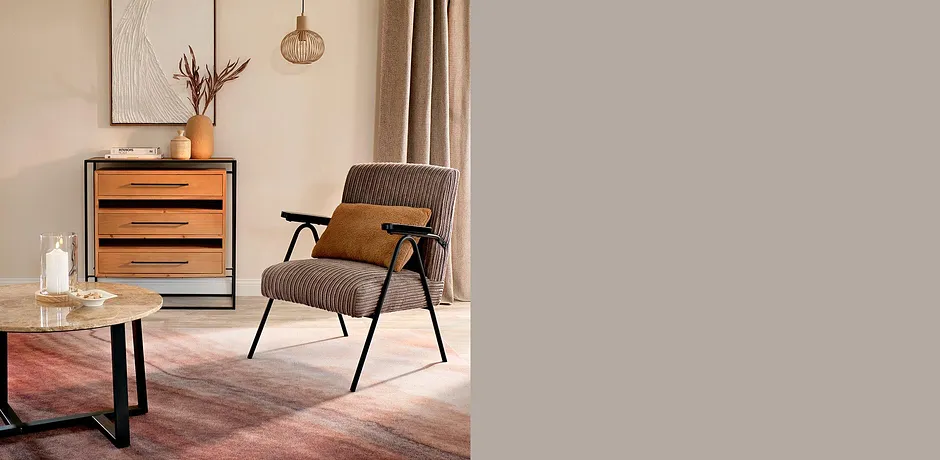 Gemütlicher Sessel mit grauem Stoff und Holzarmlehnen, passend zum warmen Interieur.