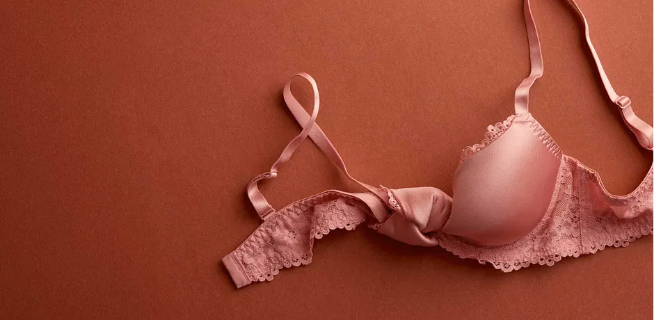 Zartrosa BH mit Spitzenbesatz auf terrakottafarbenem Hintergrund. Elegante Unterwäsche für Frauen.