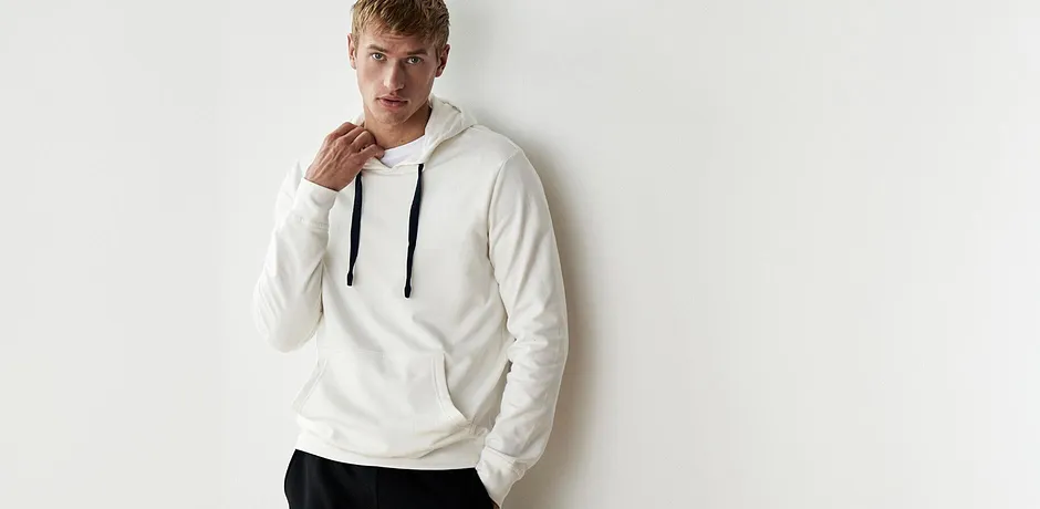 Sweat blanc à capuche avec détails noirs, associé à un pantalon foncé.