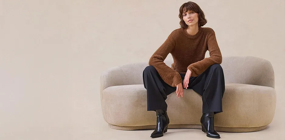 Pull marron élégant, pantalon large et bottes noires.