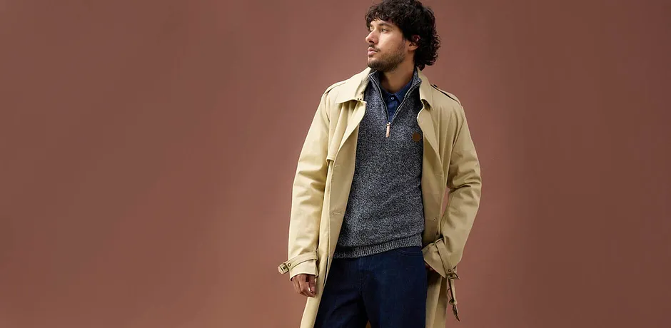 Trench-coat beige sur un pull en maille bleu-gris et jean - un look d'automne décontracté pour les journées plus fraîches.