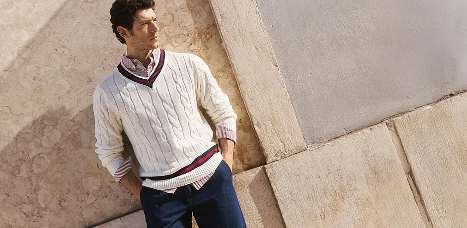 Pull élégant à motif torsadé et rayures contrastantes, associé à une chemise classique et un jean foncé.
