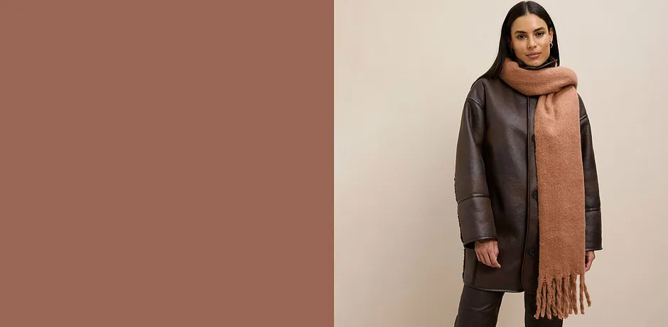 Manteau marron à manches amples, associé à un longue écharpe marron à franges.