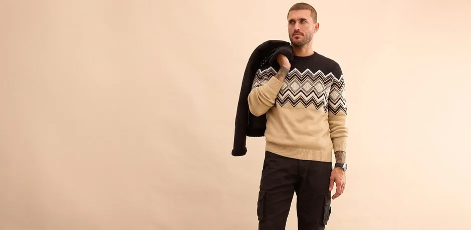 Look tendance avec veste d'hiver noire, pull à motif et jean pour les jours plus froids.