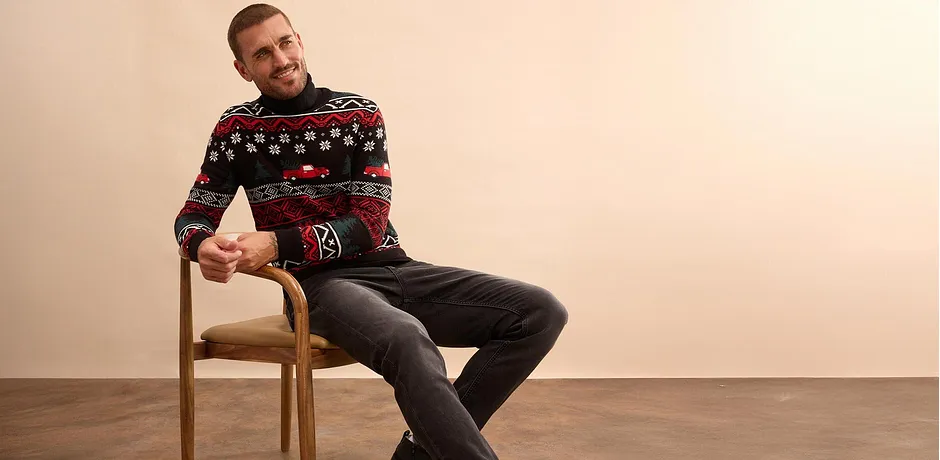 Pull de Noël à motif multicolore et jean foncé.