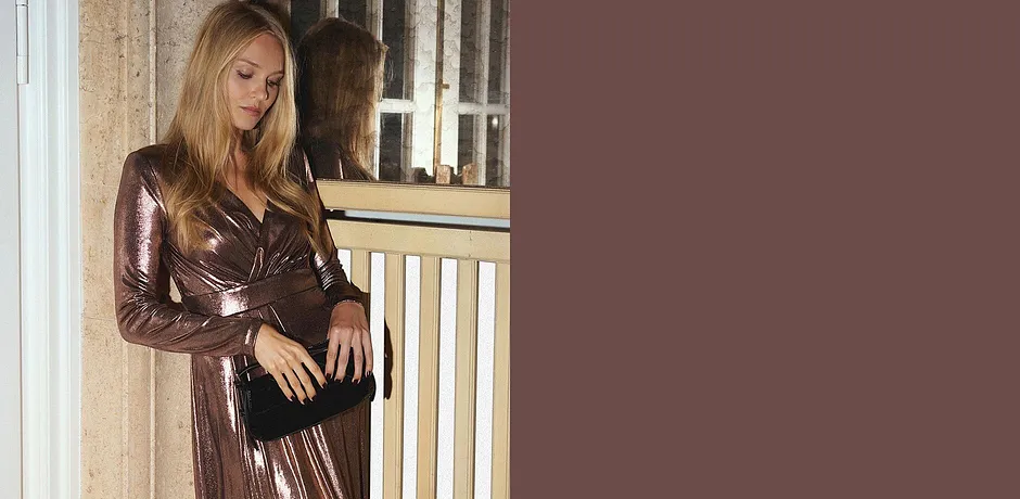 Glitzerndes Kleid mit V-Ausschnitt kombiniert mit schwarzer Tasche.