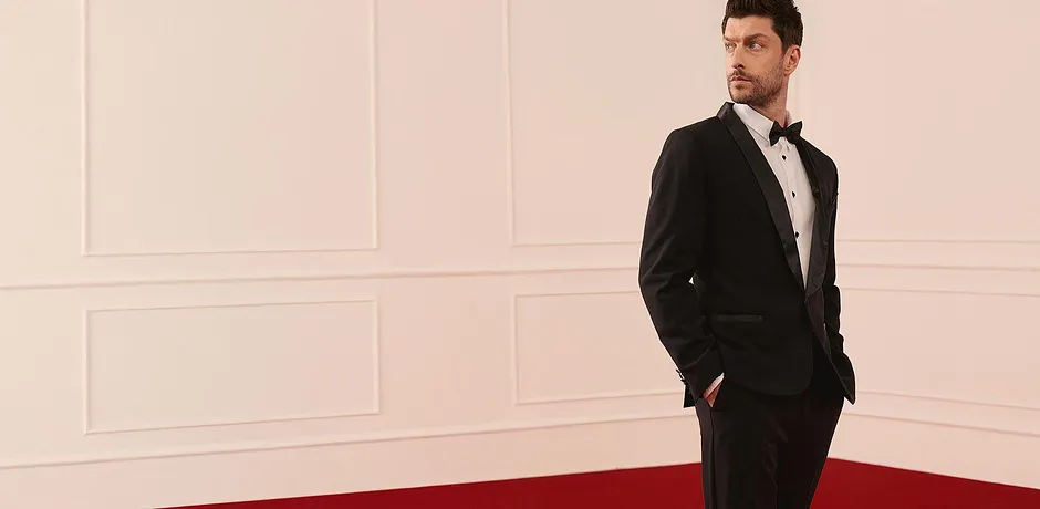 Smoking noir élégant avec chemise blanche et nœud papillon pour les occasions festives.