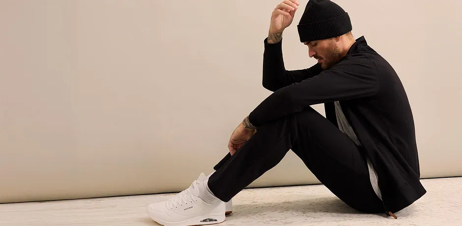 Survêtement noir avec bonnet et baskets blanches.
