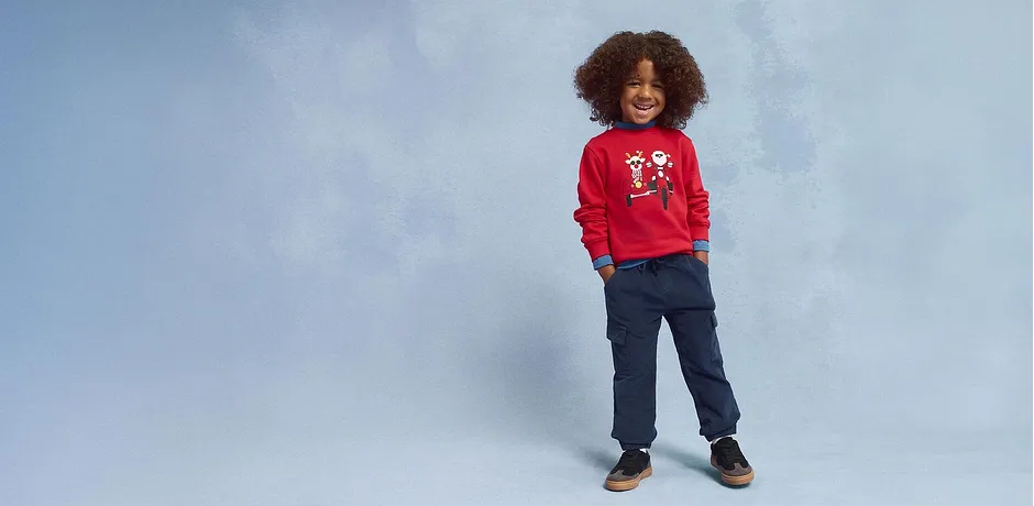 Pull de Noël rouge, jean bleu et chaussures marron.