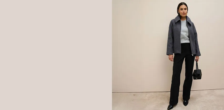 Veste grise, pull gris et pantalon noir.