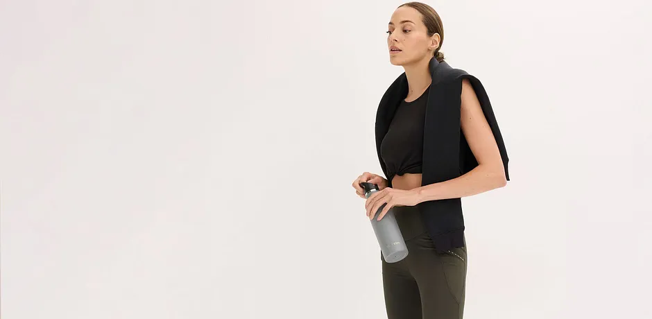 Schwarzes Sport-Top kombiniert mit olivgrüner Leggings.