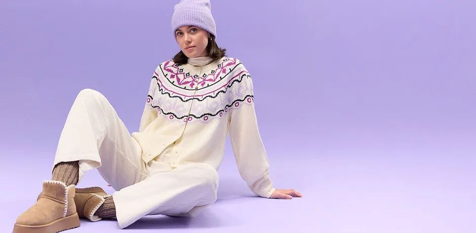 Gilet couleur crème avec motif norvégien, pantalon blanc et bonnet lilas.