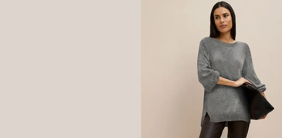 Pull long gris associé à un pantalon foncé.