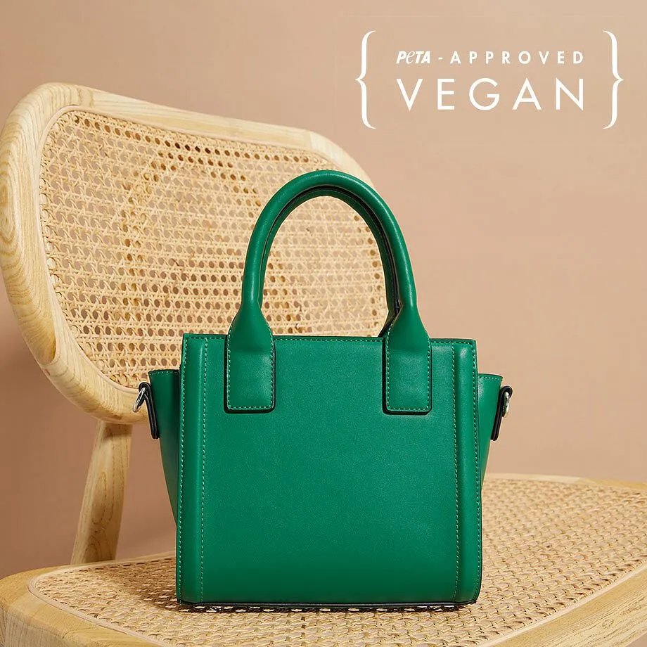 Eine kleine grüne Handtasche aus veganem Leder steht auf einem geflochtenen Stuhl.