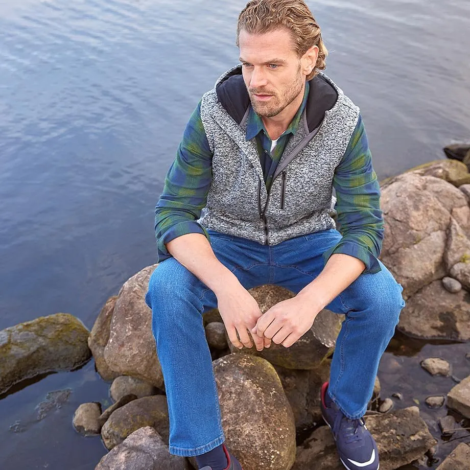 Gilet sans manches imprimé par dessus une chemise verte, associé à un jean bleu.