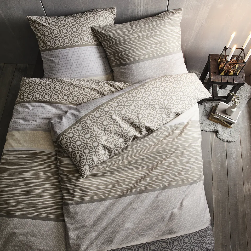 Parure de lit dans des teintes neutres avec des motifs g&eacute;om&eacute;triques.
