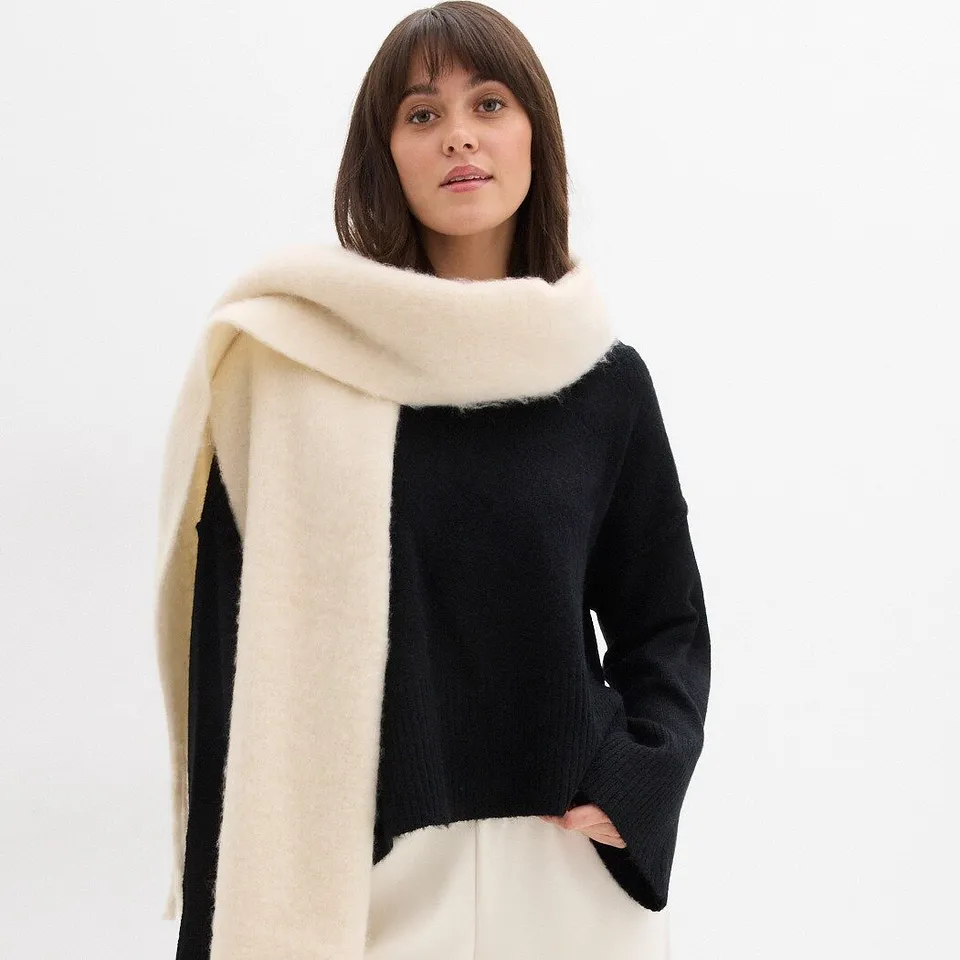 Pull noir associé à une écharpe de couleur crème.