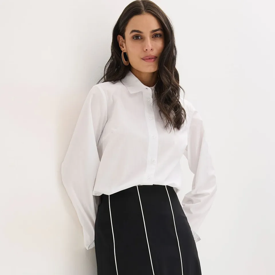 Chemisier blanc et jupe noire à rayures verticales blanches.