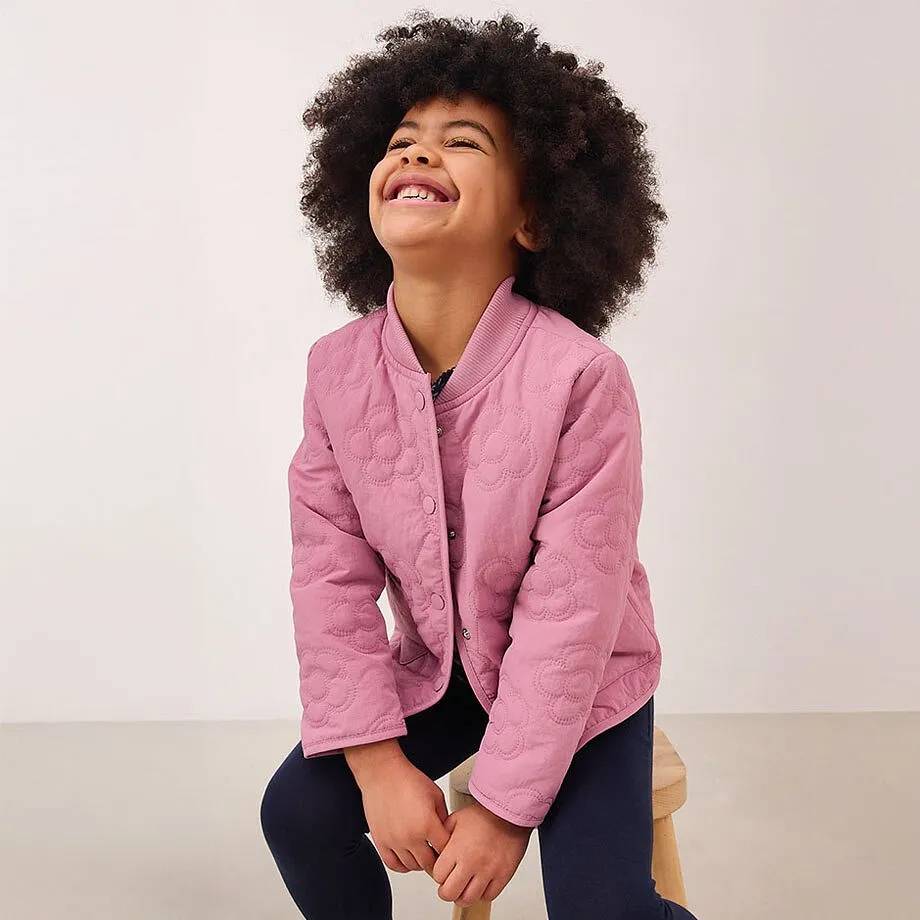 Eine rosafarbene Jacke mit Kn&ouml;pfen &uuml;ber einem dunklen Oberteil.