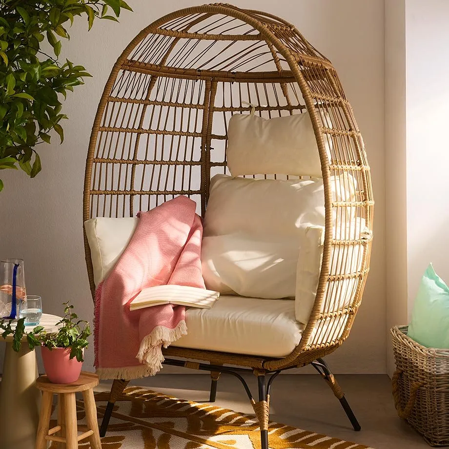 Fauteuil en rotin avec un coussin douillet de couleur claire.