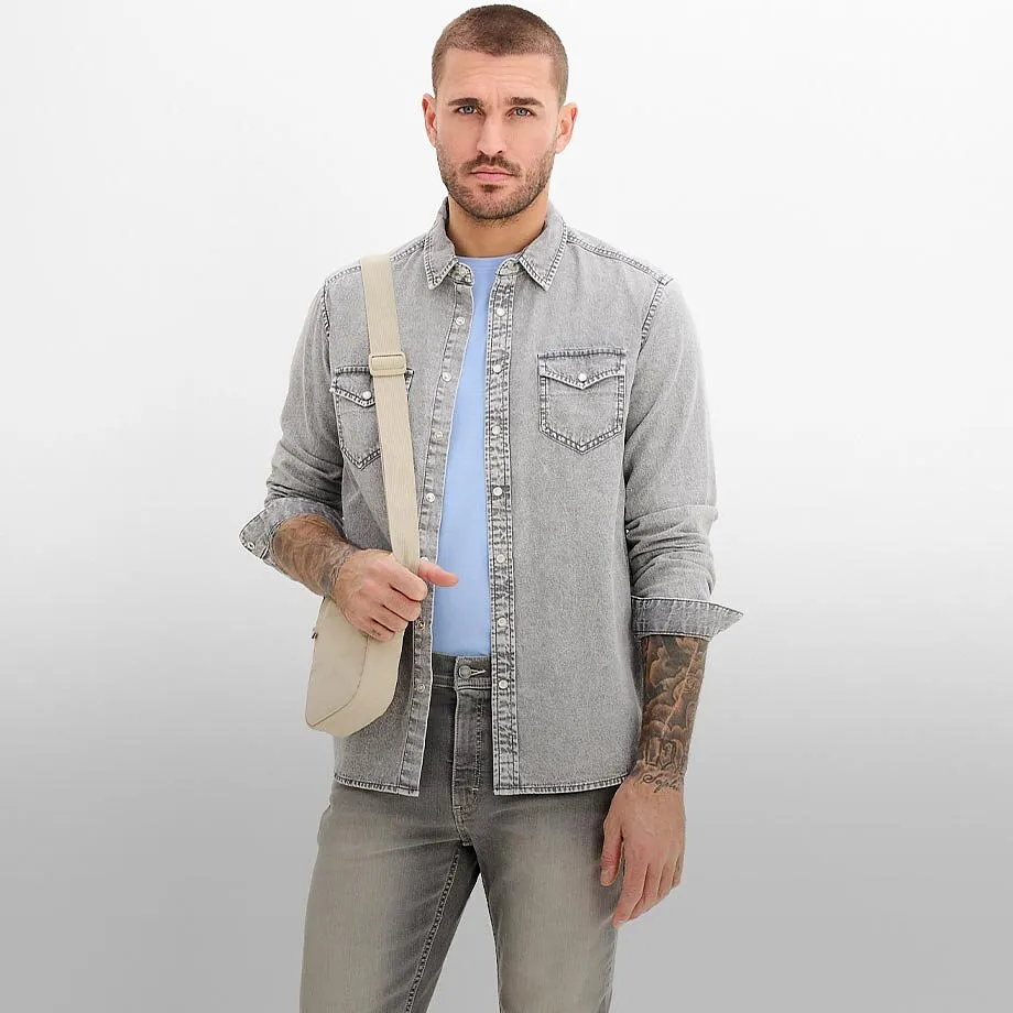 Helles Jeanshemd &uuml;ber hellblauem T-Shirt, dazu graue Jeans und eine beige Umh&auml;ngetasche.