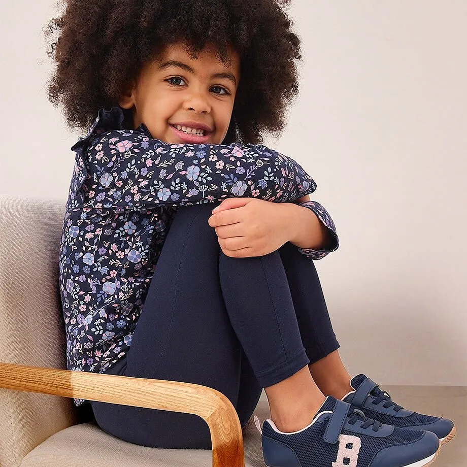 Blau dominiert das Outfit: gemustertes Oberteil, einfarbige Hose und sportliche Schuhe harmonieren perfekt.