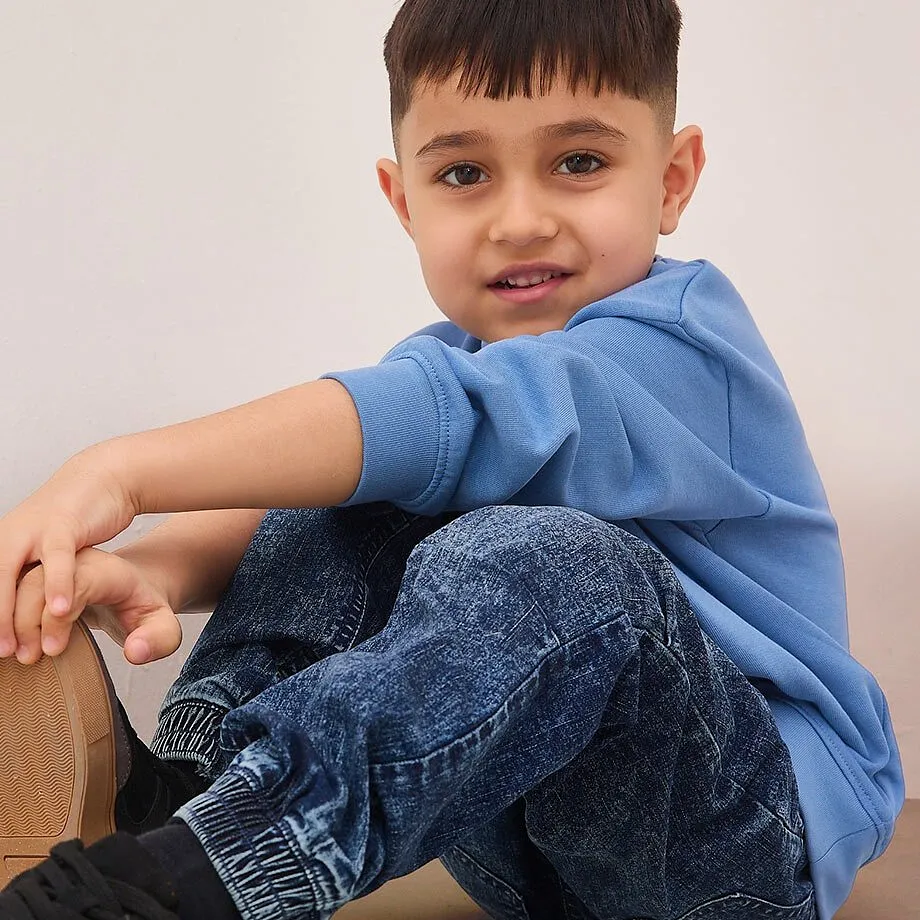 Pull bleu et jean d&eacute;lav&eacute; : une tenue d&eacute;contract&eacute;e et mode pour les gar&ccedil;ons.