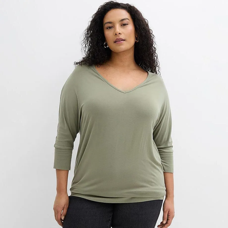 Entspannter Look mit salbeigr&uuml;nem V-Ausschnitt-Shirt und dunkler Jeans.