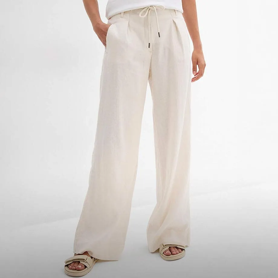 Pantalon en lin blanc associ&eacute; &agrave; un top blanc basique et des sandales confortables.