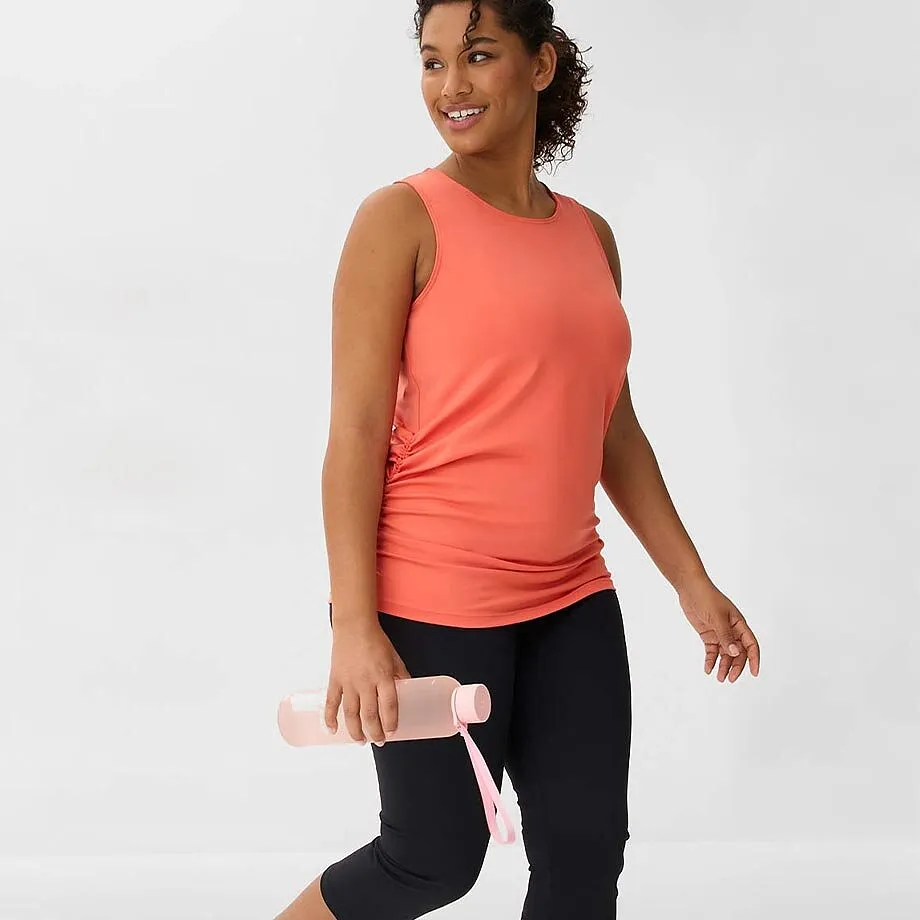 Sportliches Outfit mit korallenfarbenem Tanktop und schwarzer Caprihose.