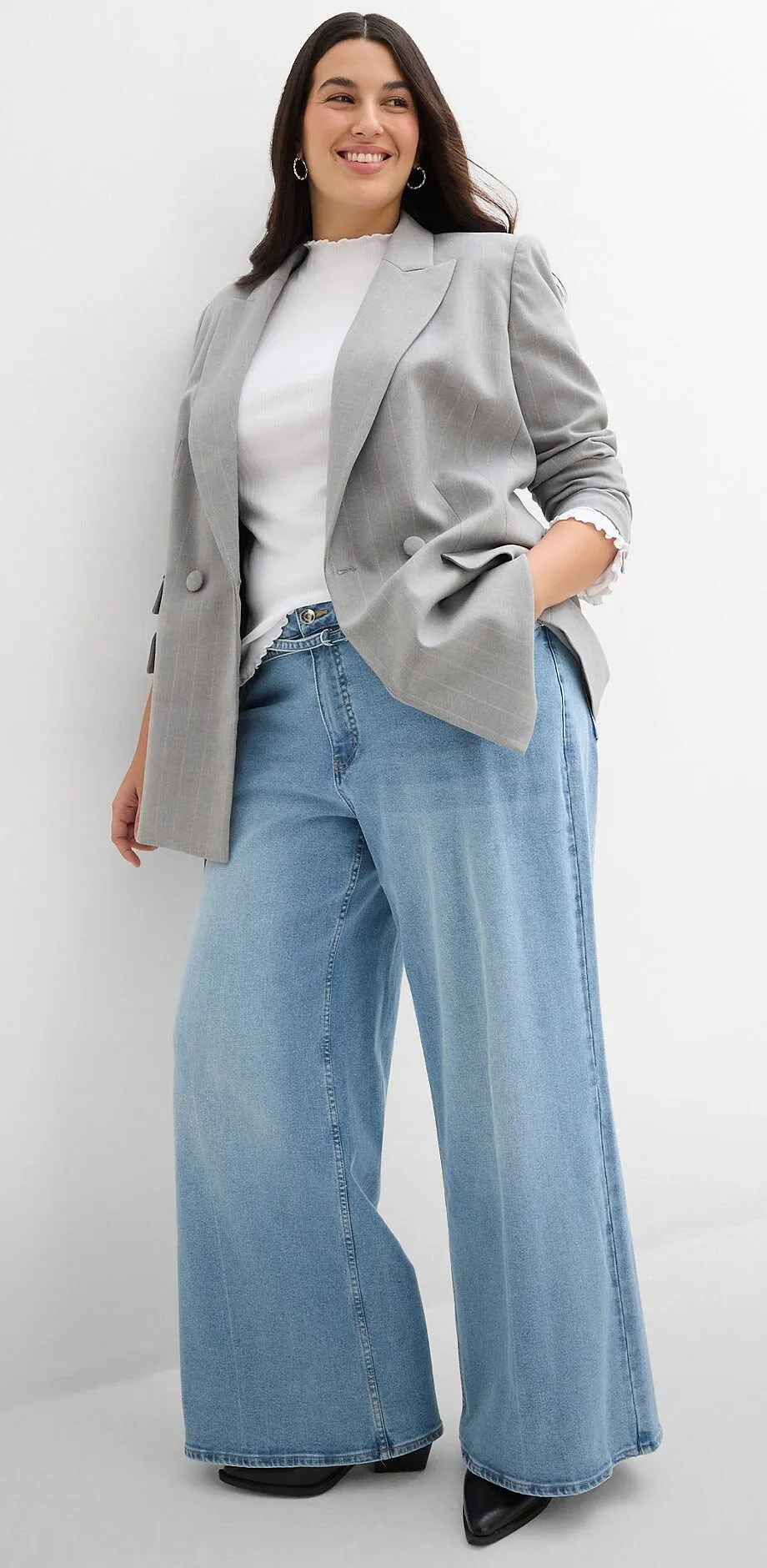 Eleganter grauer Blazer, wei&szlig;es Oberteil und weite Jeans.
