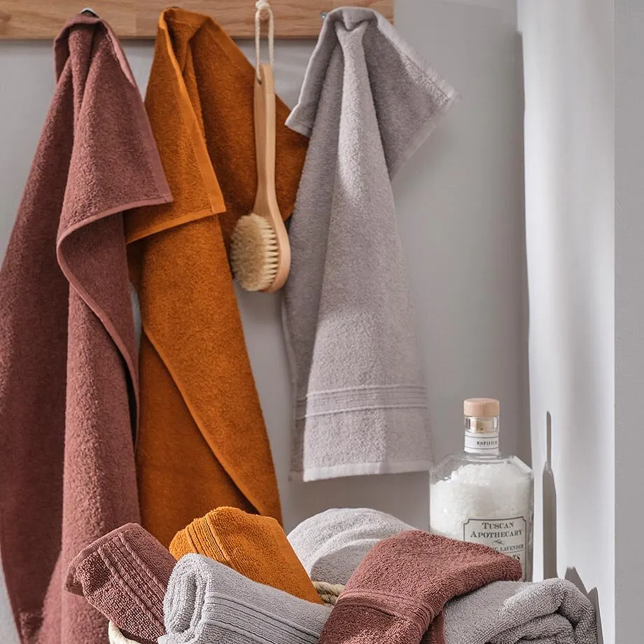 Serviettes de toilette et lavettes dans des tons terreux chauds.