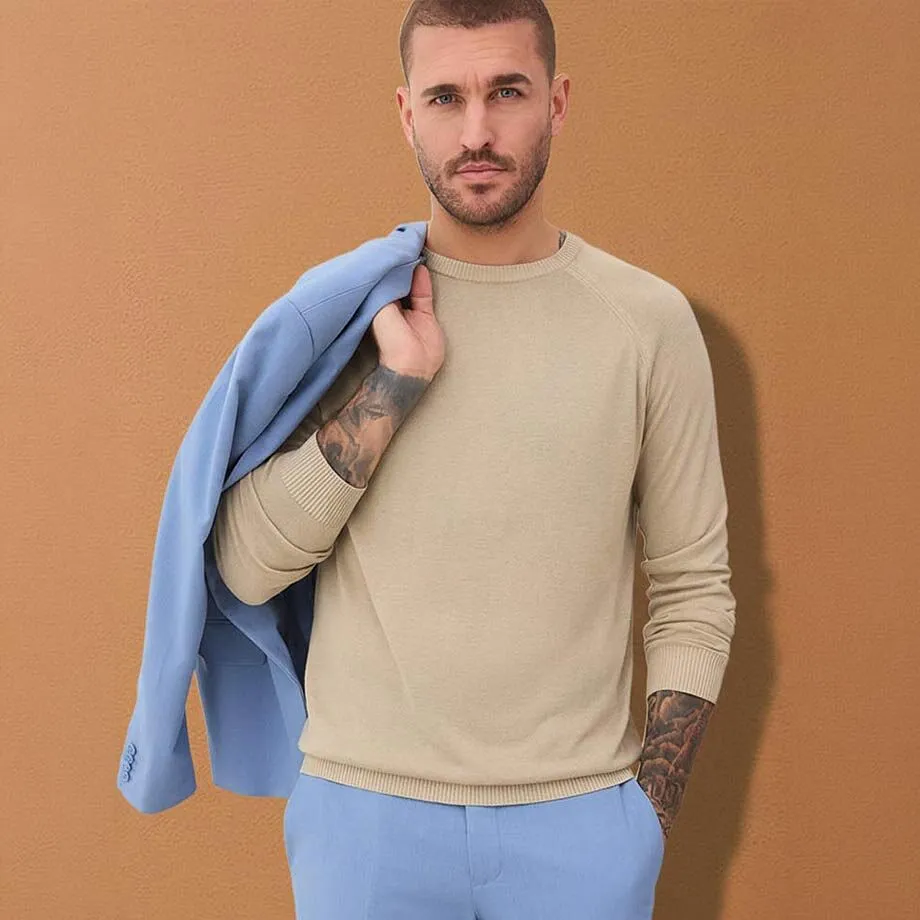 Pull de couleur claire, veste de costume bleue & pantalon assorti.