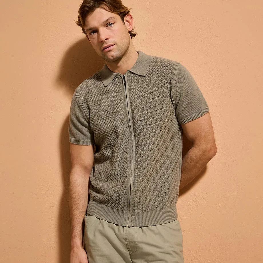 Polo gris en tricot avec fermeture zipp&eacute;e, pantalon beige.