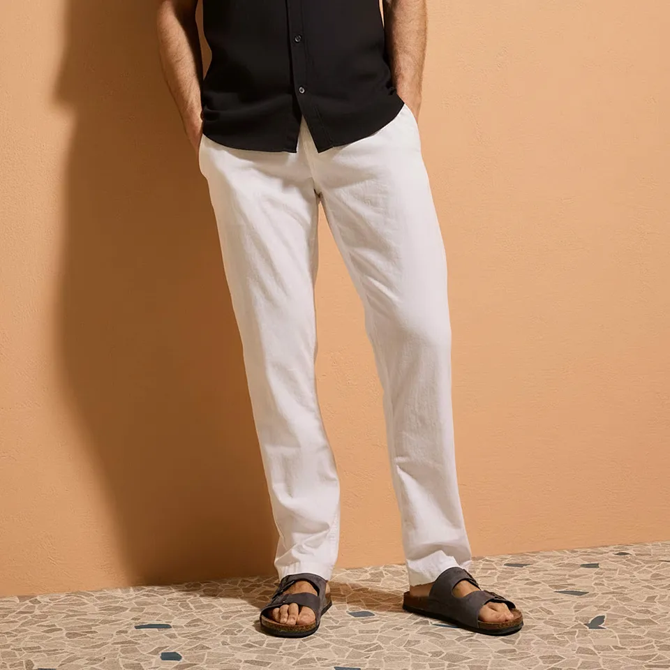 Contraste chic : chemise noire et pantalon blanc estival. Des sandales d&eacute;contract&eacute;es compl&egrave;tent ce look.