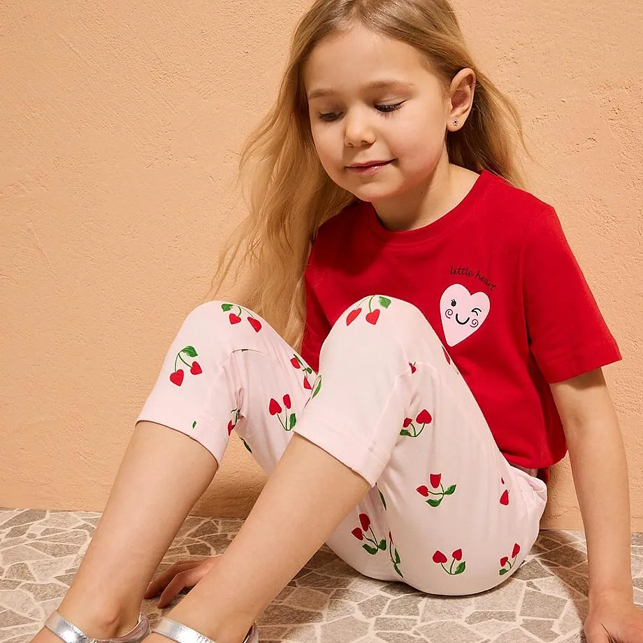 Ein kleines M&auml;dchen tr&auml;gt ein rotes T-Shirt mit Herz-Motiv.