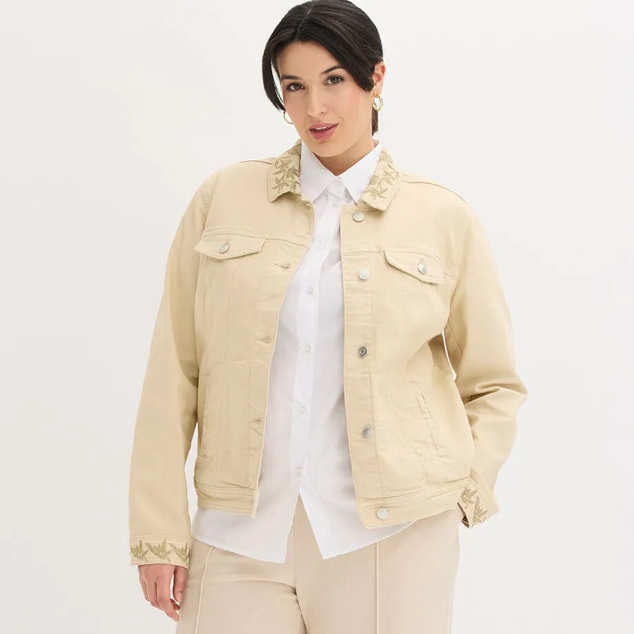 Veste beige en twill avec broderie sur un chemisier blanc.
