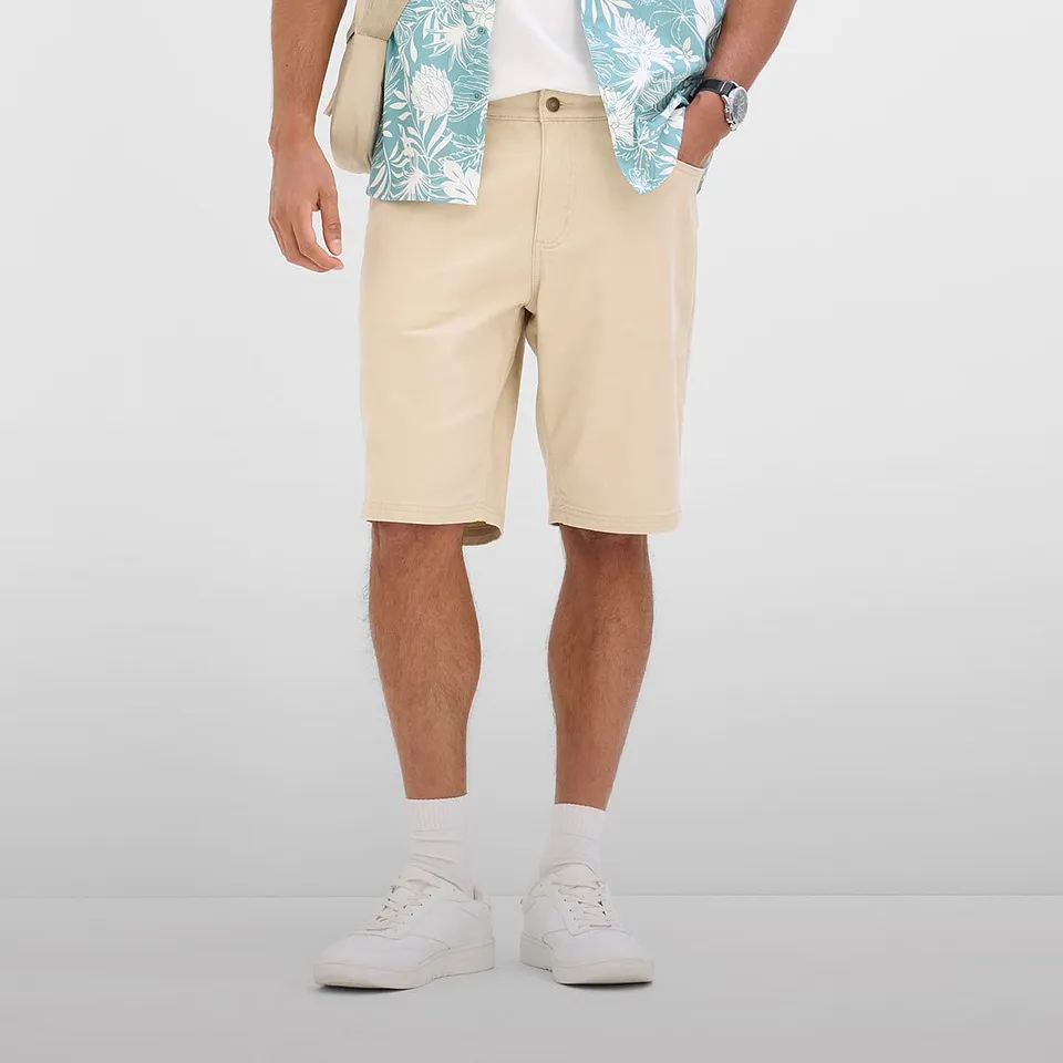 Tenue estivale et d&eacute;contract&eacute;e comprenant un bermuda beige, une chemise imprim&eacute;e et des sneakers blanches.