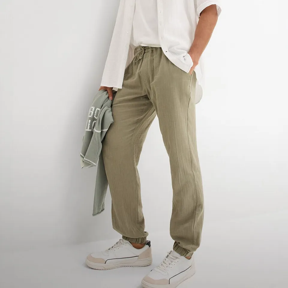 Pantalon d&eacute;contract&eacute; vert olive avec T-shirt blanc et chemise claire.