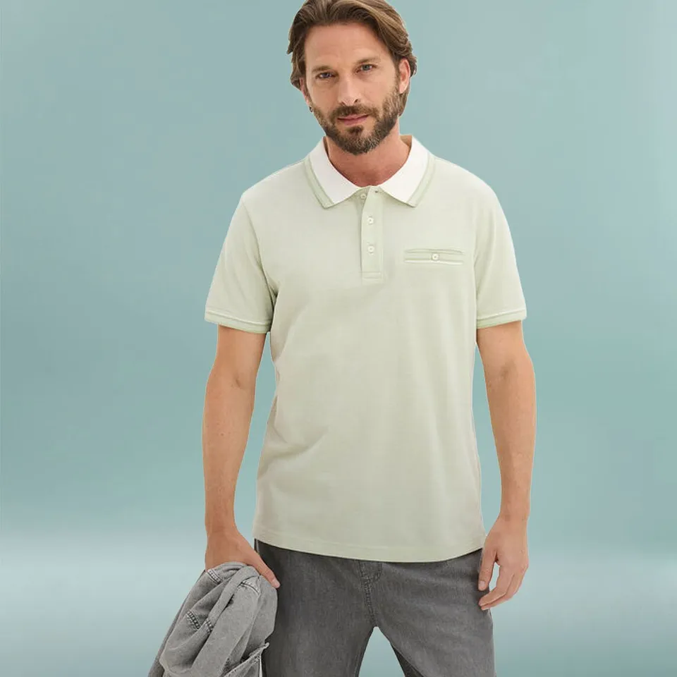 Homme v&ecirc;tu d'un polo vert clair &agrave; col blanc et d'un pantalon gris.