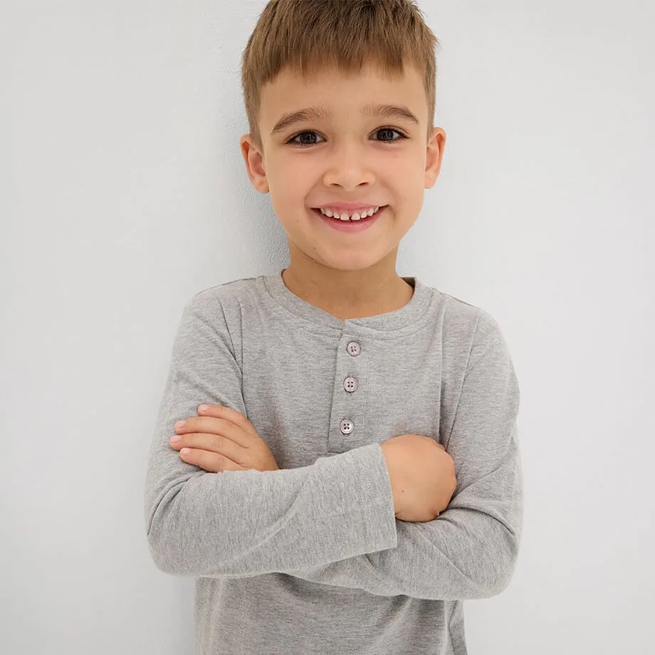Gar&ccedil;on v&ecirc;tu d'un T-shirt gris &agrave; manches longues avec boutons au col.