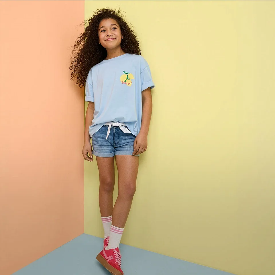 Sommer-Outfit mit hellblauem T-Shirt, Jeansshorts und bunten Sneakers.