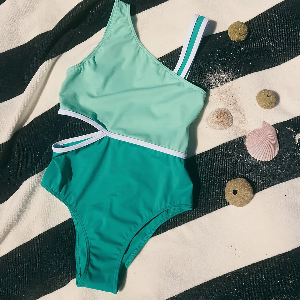 Maillot 1 pi&egrave;ce enfant couleur turquoise avec rayures blanches dans une coupe sportive.