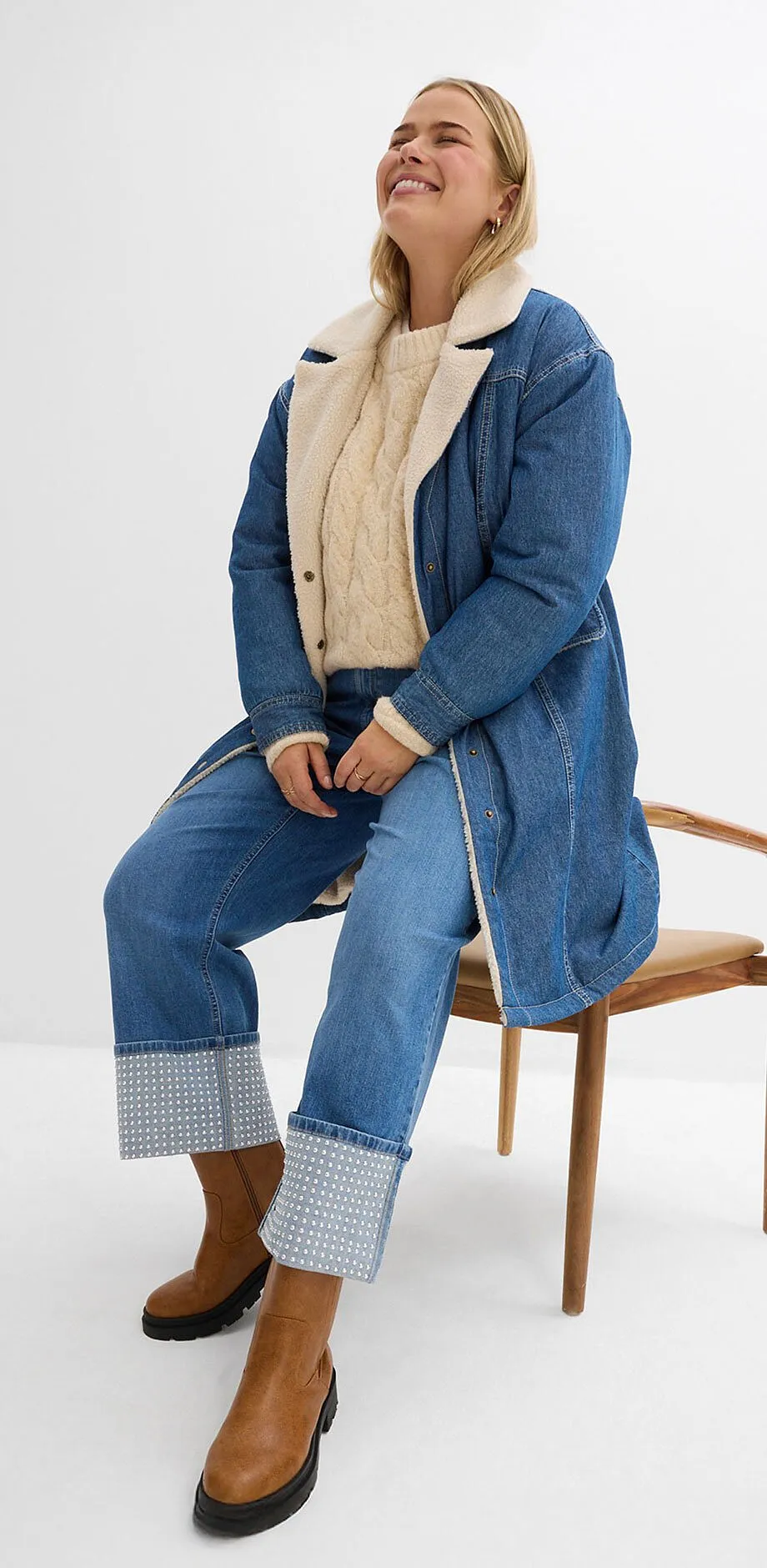 Look en jean avec un manteau long, un pull beige et un jean.