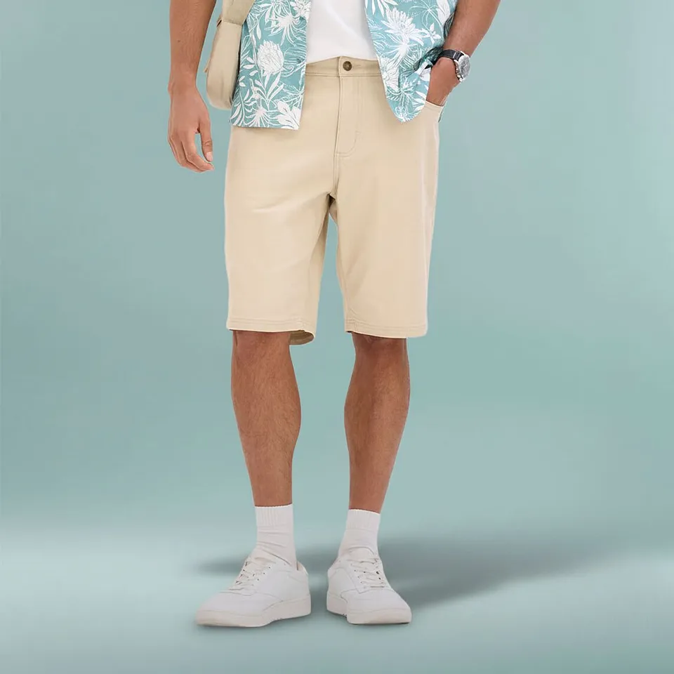 Tenue estivale et d&eacute;contract&eacute;e comprenant un bermuda beige, une chemise imprim&eacute;e et des sneakers blanches.