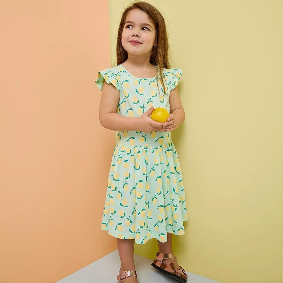 Ein M&auml;dchen tr&auml;gt ein t&uuml;rkises Kleid und Sandalen.