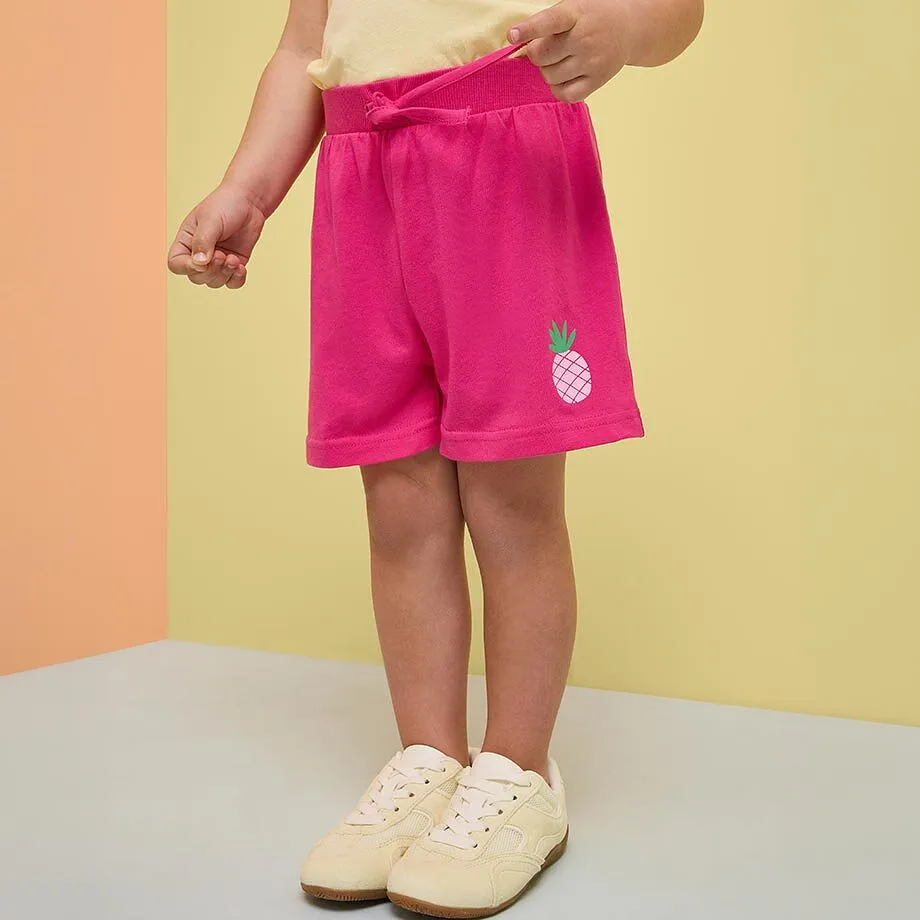 Pinke Shorts mit Ananas-Motiv und helles Oberteil.